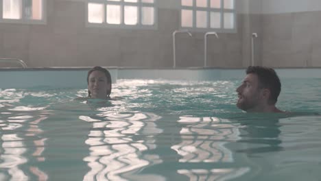 a-couple-swims-in-an-indoor-pool