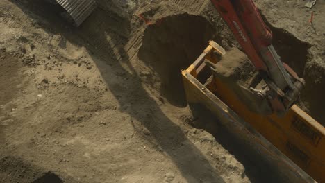 Slow-motion-excavator-scoops-dirt-and-moves-to-pile-on-construction-site