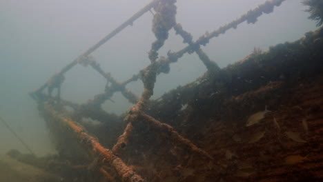 Underwater-foggy-shot-of-deck-wreckage-with-fishes-around