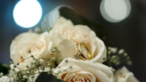 Bouquet-of-white-roses-with-shiny-wedding-rings-between-their-petals