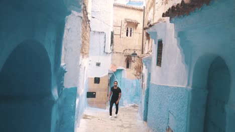 A-young-man-getting-out-of-a-small-street-in-chefchaouen,-Morocco