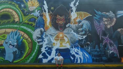 A-person-sits-and-stands-in-front-of-an-graffiti-art-mural-dedicated-to-Dragon-Ball-anime-series
