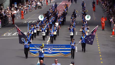 Schüler-Der-Blaskapelle-Der-Mackay-North-State-High-School-Treten-Auf-Und-Laufen-Während-Der-Anzac-Day-Parade-Die-Straße-Entlang,-Um-Derer-Zu-Gedenken,-Die-Gedient-Und-Opfer-Gebracht-Haben