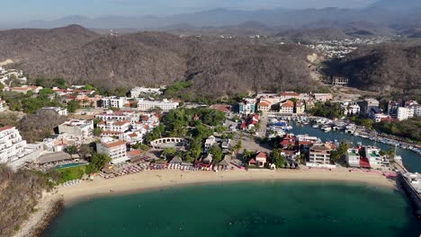 Bahia-de-Santa-Cruz-Huatulco,-Oaxaca,-revealing-charming-town-of-Huatulco-shown-below