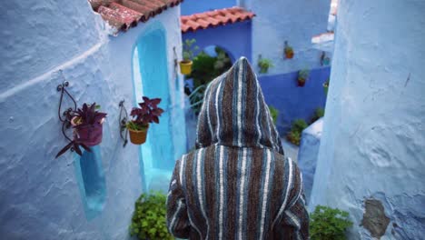 Un-Hombre-Vestido-Con-Un-Suéter-De-Chefchaouen-Caminando-Por-Una-Pequeña-Y-Hermosa-Calle-Con-Paredes-Azules-En-Chefchaouen-Marruecos
