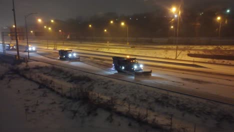 Group-of-Snow-Pusher-Cars-clearing-highway-at-night