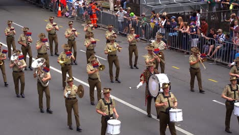 The-Australian-Army-Band-Corps-performs-musical-instruments-while-marching-down-Adelaide-Street,-cheered-on-by-crowds-during-the-Anzac-Day-parade-in-Brisbane-city