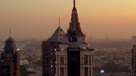 Vista-Aérea-De-La-Mitad-Superior-De-La-Torre-UB-En-El-Distrito-De-Negocios-De-Bengaluru-Con-Cielos-Anaranjados-Al-Atardecer-En-El-Fondo