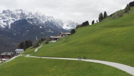 Mountain-bike-athletes-train-in-the-spectacular-scenic-Dolomites-spring-landscape,-DRONE