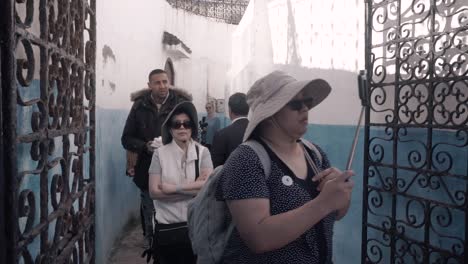 Group-of-tourists-walking-on-small-street-inside-old-medina-of-Chefchaouen,-Morocco