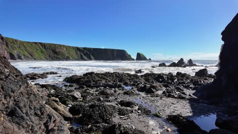 Brandung-Bricht-Am-Felsigen-Strand-Mit-Klippen-Und-Felsnadeln-Ballydwane-Copper-Coast-Waterford-Irland-An-Einem-Perfekten-Frühlingstag