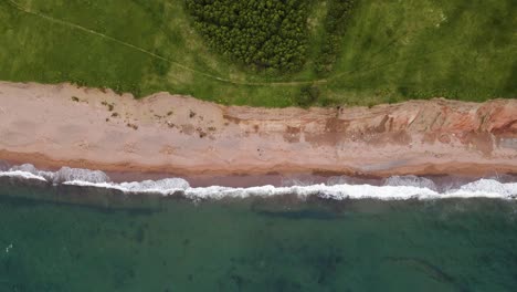 Disparo-De-Un-Dron-Que-Va-Hacia-La-Izquierda-Siguiendo-El-Hermoso-Contraste-Donde-Los-Enormes-Acantilados-Se-Encuentran-Con-La-Playa-Y-El-Océano-Atlántico-Ubicado-En-La-Isla-De-Cabo-Bretón-En-La-Provincia-De-Nueva-Escocia,-Canadá.