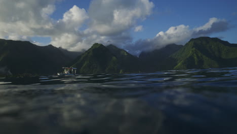 In-water-view-of-support-boats-for-surfers-and-Tahitian-valley-mountains-at-Teahupoo