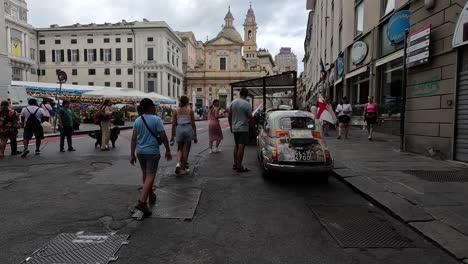 Handheld-clip-walking-through-busy-city-streets-in-Italy,-showing-tourists-and-bustling-market,-and-traditional-city-buildings-in-the-background