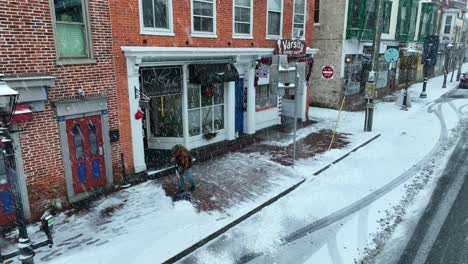 Man-shoveling-sidewalk-in-front-of-town-store