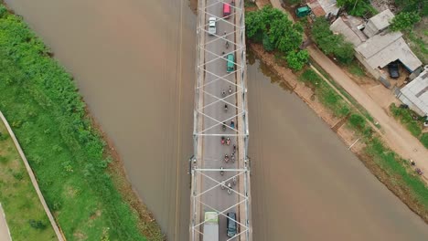Aerial-view-drone-footage-overhead-shot-above-the-Citarum-bridge-over-the-Citarum-river-Indonesia,-with-traffic,-cars-and-trucks,-crossing-in-morning-light