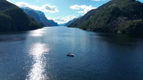 Tourists-on-private-charter-RIB-fjord-cruise-in-Norway,-Aerial-with-Veafjord-in-background