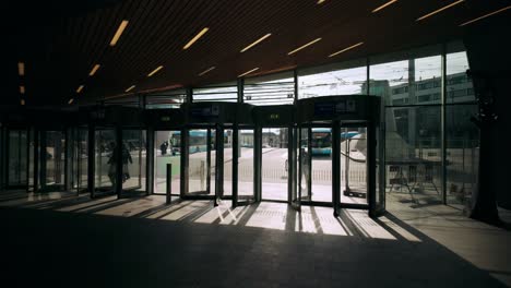 Rotating-arrival-and-departure-revolving-doors-at-Dutch-train-station-in-Arnhem-backlight