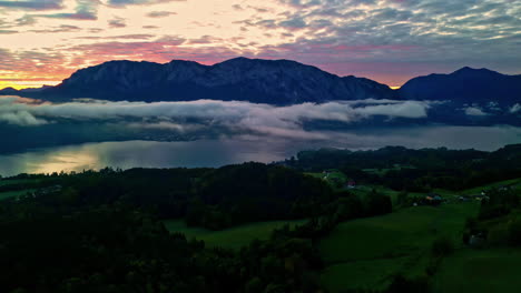 Aerial-landscape-view-of-Alps-in-Austria-during-sunset-with-Attersee-lake-and-clouds-above-it