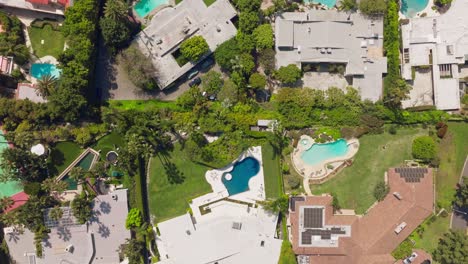 Drone-Flying-Over-Beverly-Hills-Estates,-Luxury-Homes-with-Sparkling-Pools-on-Sunny-Day