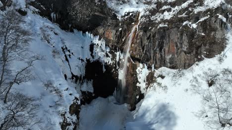 Static-shot-of-waterfall-from-melting-snow,-camera-flying-through-gorge-revealing-waterfall-area