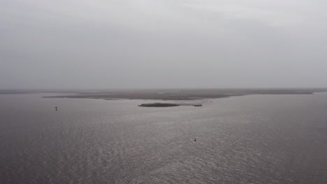 Wide-aerial-shot-of-historic-Fort-Sumter-in-Charleston-Harbor-from-Fort-Moultrie-on-Sullivan's-Island-during-a-gloomy-day-with-low-visibility-in-South-Carolina