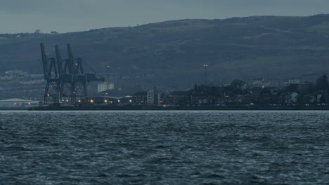 Distant-docks-and-large-loading-cranes-on-the-water-front-of-a-town