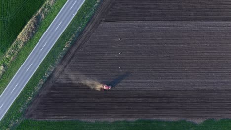 Agricultural-tractor-working-on-farmland,-plowing-field-in-spring,-aerial-shot