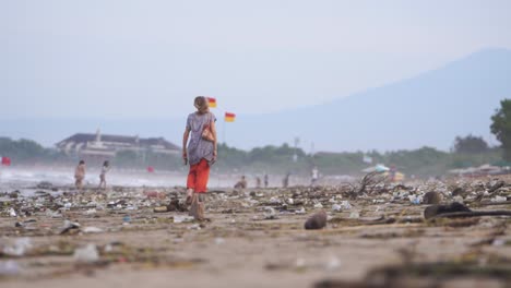 Touristen-Gehen-An-Der-Küste-Von-Kuta-Bali-Entlang,-Obwohl-Es-Berge-Von-Müll,-Plastik-Und-Flaschen-Gibt