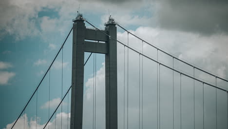 Timelapse-close-up-shot-with-the-top-of-a-suspended-bridge,-clouds-drifting-in-the-background,-HDR