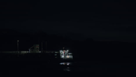 Ferry-Esperando-En-El-Muelle-Por-La-Noche,-Disparo-Estático-Distante