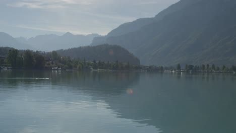 Un-Pato-A-Lo-Lejos-Nadando-Tranquilamente-Con-Una-Vista-Perfecta-Del-Pintoresco-Puerto-Mientras-Siguen-Las-Ondas-|-Ladera-Rural-Europea-Con-Un-Gran-Lago.