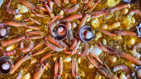 Kochen-Eines-Großen-Traditionellen-Spanischen-Paella-Gerichts-Mit-Meeresfrüchten,-Garnelen,-Jakobsmuscheln-Und-Kaisergranat-(Nephrops-Norvegicus),-Lecker-Gekochter-Reis-Mit-Meeresfrüchten,-Marbella,-Spanien,-4K-Aufnahme