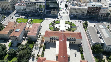 A-drone-captures-Athens,-Greece,-flying-over-the-University-of-Athens,-showcasing-the-building's-rear-and-the-road-in-front