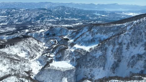 Disparo-De-Drone-Desde-Arriba-De-La-Cumbre-De-Una-Montaña-Nevada,-Cámara-Empujando-Hacia-Adelante-Y-Panorámica-Hacia-Arriba