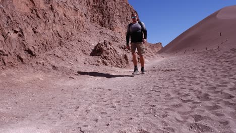 Un-Excursionista-Masculino-Caminando-Por-Un-Acantilado-De-Arena-Del-Desierto-En-Chile-Se-Acerca-A-La-Cámara