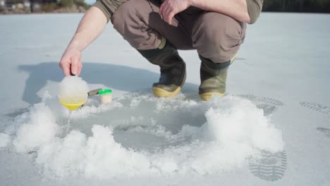 Pescador-Quitando-Hielo-En-El-Hoyo-De-Pesca-Con-Pala-De-Plástico