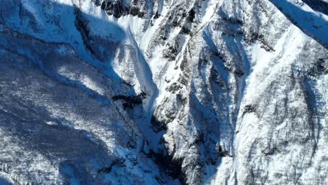 Aerial-wide-establishing-pan-up-reveal-shot-of-Japan's-mount-myōkō,-on-a-clear-winter-day,-a-volcanic-mountain-in-Myoko-Togakushi-Renzan-National-Park-region