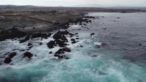 Grey-ocean-waves-crash-against-jagged-shore-rocks,-central-Chile-coast