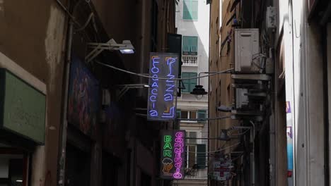 Slow-motion-clip-panning-down-from-neon-signs-along-narrow-alleyway-to-people-walking-past