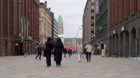 La-Gente-En-Helsinki,-Finlandia,-Camina-Por-La-Calle-Peatonal-De-Azulejos-Del-Centro-De-La-Ciudad.