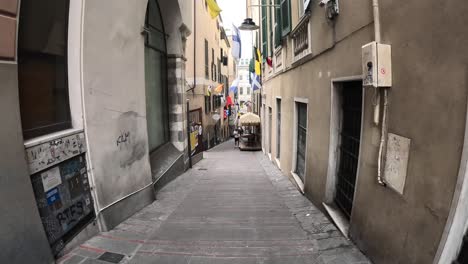 Timelapse-clip-walking-through-paved-streets-in-Genoa,-Italy-with-tall-buildings-and-people-walking-past