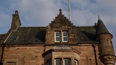 Red-stone-house-with-roof-and-windows-on-sunny-day-in-town