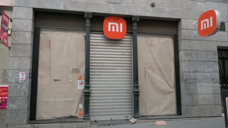 Pedestrians-walk-past-a-closed-Chinese-multinational-technology-and-electronics-brand-Xiaomi-flagship-store-in-Madrid,-Spain