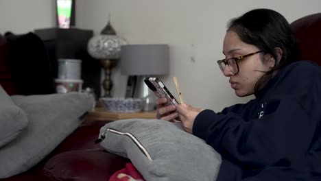 Retrato-De-Una-Mujer-Con-Anteojos-Usando-Un-Teléfono-Inteligente-En-Casa