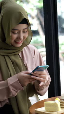 An-upwardly-mobile-Asian-Muslim-woman-enjoying-a-relaxing-moment-in-the-coffee-shop-on-a-bright-sunny-day