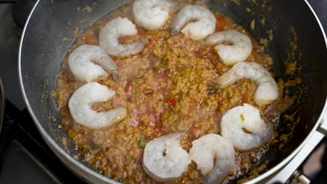 Una-Persona-Añade-Delicadamente-Gambas-A-Una-Salsa-Caliente-Y-Burbujeante-En-Un-Plato,-Capturada-En-Cámara-Lenta,-Mostrando-Su-Experiencia-Culinaria-Y-El-Placer-De-Cenar.