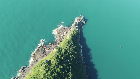 Das-Zenitalbild-Fängt-Die-Raue-Schönheit-Einer-Felsigen-Insel-Inmitten-Eines-Atemberaubenden-Blauen-Meeres-Ein