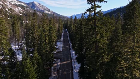 Smooth-motion-forward-shot-above-road-moving-through-evergreen-forest-with-mountains-in-the-background-in-Cle-Elum,-Washington-State