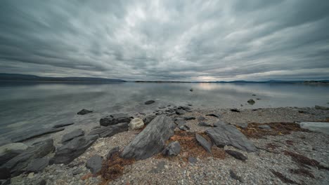 Stormy-clouds-move-fast-above-the-mirrorlike-surface-of-the-fjord-and-the-pebble-beach